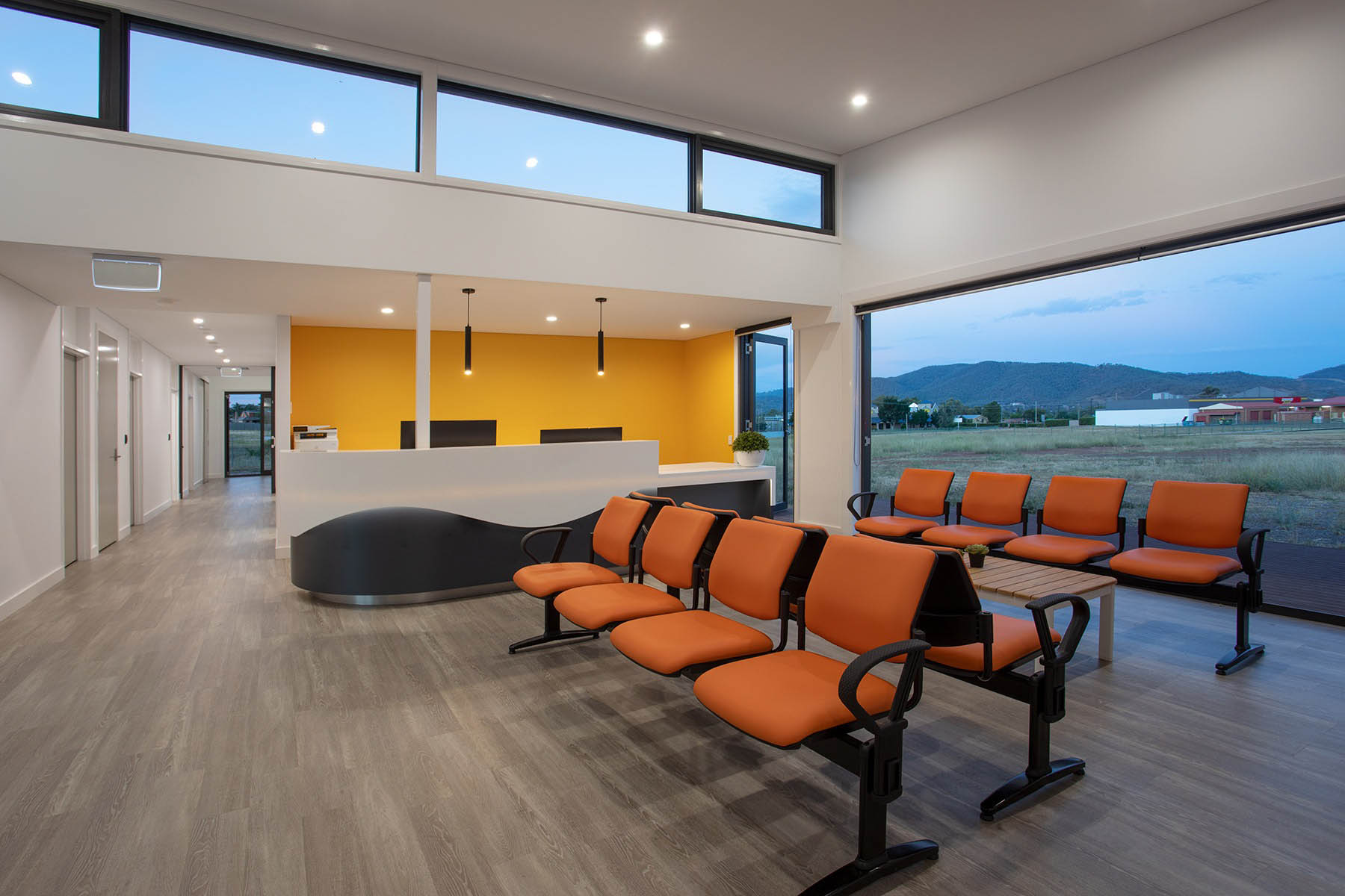 Modern, inviting waiting room and desk at a medical clinic by medical architecture and clinics by design by Space for Health
